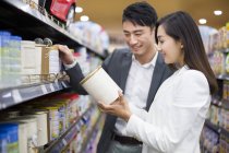 Chinese couple choosing goods in supermarket — Stock Photo
