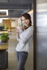 Chinesin steht mit Tasse Kaffee im Büro — Stockfoto