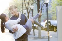 Chinese man carrying girlfriend in arms — Stock Photo