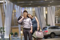 Chinese couple standing with shopping bags in mall — Stock Photo