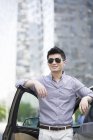 Китайська людина стоїть перед автомобіля і посміхається — стокове фото