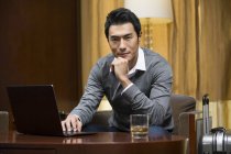 Chinesischer Geschäftsmann benutzt Laptop am Tisch im Hotelzimmer — Stockfoto