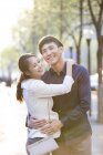Китайская пара обнимается и улыбается на улице — стоковое фото