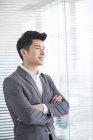 Uomo d'affari cinese in piedi in ufficio con le braccia incrociate — Foto stock