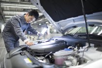 Mécanicien automobile chinois examinant moteur de voiture — Photo de stock