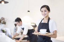 Китайская официантка, стоящая с чашкой кофе — стоковое фото