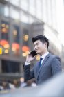 Hombre de negocios chino hablando por teléfono en la ciudad - foto de stock