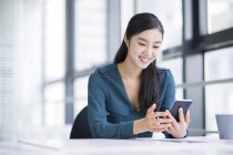 Chinesische Geschäftsfrau nutzt Smartphone im Büro — Stockfoto
