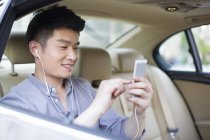 Hombre chino escuchando música en el asiento trasero del coche - foto de stock