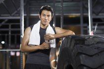 Chinois reposant à la salle de gym avec serviette et eau — Photo de stock