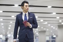 Chinese businessman holding passport in airport — Stock Photo