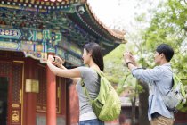 Chinese couple taking pictures with smartphones in Lama Temple — Stock Photo