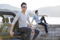 Chinese men sitting on lakeside and smiling — Stock Photo