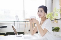 Chinese woman listening to music in coffee shop — Stock Photo