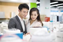 Китайская пара выбирает мультикукер в магазине электроники — стоковое фото