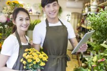 Fleuristes chinois debout avec tablette numérique dans la boutique — Photo de stock