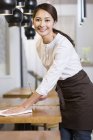 Chinese waitress wiping table in cafe — Stock Photo