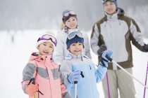 Famiglia cinese in posa presso la stazione sciistica con bastoni da sci — Foto stock
