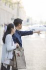 Mature chinese couple gesturing on street with shopping bags — Stock Photo