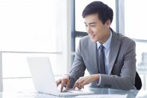 Empresário chinês usando laptop no escritório — Fotografia de Stock