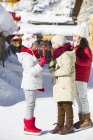 Niños chinos comiendo halcones confitados en pueblo nevado - foto de stock