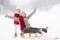 Chinese granddaughter pushing grandmother on sled — Stock Photo