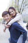 Cinese uomo holding piggy indietro fidanzata su strada — Foto stock