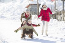 Chinese family playing with sled in snow — Stock Photo