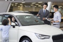 Chinesischer Autohändler hilft Familie bei der Wahl des Autos im Showroom — Stockfoto