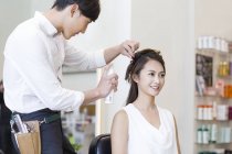 Peluquería china trabajando en el cabello del cliente - foto de stock