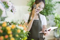 Chinês feminino lojista falando no telefone no loja — Fotografia de Stock