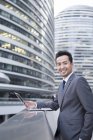 Chinese businessman using laptop in financial district — Stock Photo