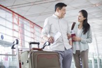 Зрелая китайская пара, стоящая в аэропорту с билетами — стоковое фото