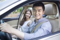 Chinese couple sitting in car and looking in camera — Stock Photo