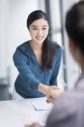 Chinese woman shaking hands with businessman — Stock Photo