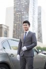 Chinese chauffeur standing in front of car — Stock Photo