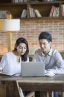 Chinese man and woman using laptop in cafe — Stock Photo