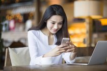 Китаянка использует смартфон в кафе — стоковое фото