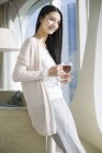 Chinese woman holding cup of black tea in home interior — Stock Photo