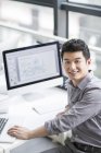 Chinesischer Geschäftsmann sitzt am Arbeitsplatz im Büro — Stockfoto