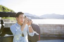 Hombre chino tomando fotos en la orilla del lago - foto de stock