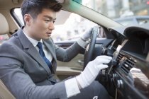 Chinese chauffeur using smartphone in car — Stock Photo