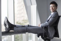 Homme d'affaires chinois assis sur une chaise et regardant à la caméra — Photo de stock