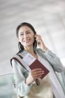 Mature chinese woman talking on phone at airport — Stock Photo