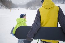 Padre e hijo caminando con tablas de snowboard en la nieve, primer plano - foto de stock