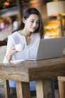 Chinese woman using laptop in cafe — Stock Photo