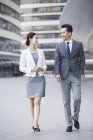Chinese business people walking and talking on street — Stock Photo