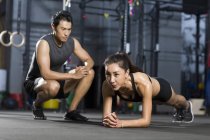 Mujer china haciendo flexiones con entrenador en el gimnasio - foto de stock