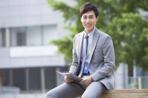 Chinese businessman sitting on bench with fold — Stock Photo