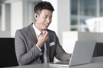 Direttore di vendita cinese con auricolare utilizzando laptop — Foto stock